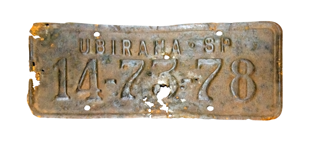 Uma placa de identificação de veículo muito antiga de lata, com corrosões.